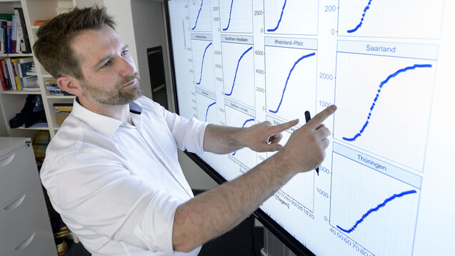 Thorsten Lehr, Professor für Klinische Pharmazie der Universität des Saarlandes, erklärt die Schaubilder des Covid-Simulators. (Foto: Universität des Saarlandes)