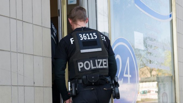 Ein Polizist betritt am Donnerstag ein Büro einer Pflegefirma in Berlin. Mit einem Großaufgebot von Beamten ist die Berliner Polizei gegen organisierten Betrug bei Pflegeabrechnungen vorgegangen. (Foto: Paul Zinken/dpa)