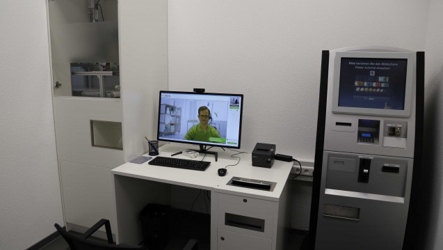 So funktionert der DocMorris-Arzneimittel-Abgabeautomat: Am Schreibtisch kann sich der Kunde via Video-Schaltung pharmazeutisch beraten lassen, links daneben erfolgt die Medikamentenausgabe über den Automaten. Rechts neben dem Schreibtisch ist das Bezahl-Terminal aufgebaut. (Foto: diz)