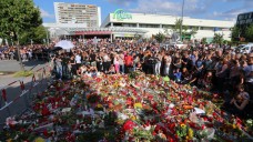 Blumenmeer und stilles Gedenken an die Toten: Trauernde treffen sich am Sonntag beim Olympia-Einkaufszentrum in München. (Foto: dpa)